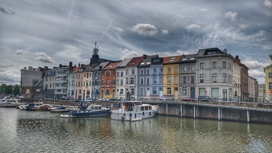Portus Ganda in Ghent features a calm body of water reflecting the surrounding landscape and architecture.
