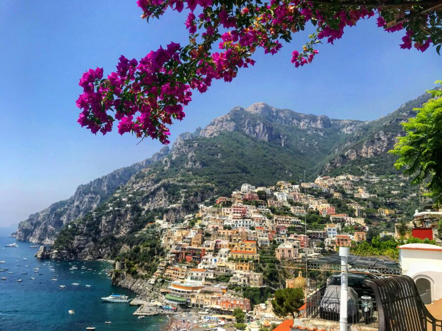 Picturesque Positano view with colorful houses, bougainvillea, cliffs, and Tyrrhenian Sea.