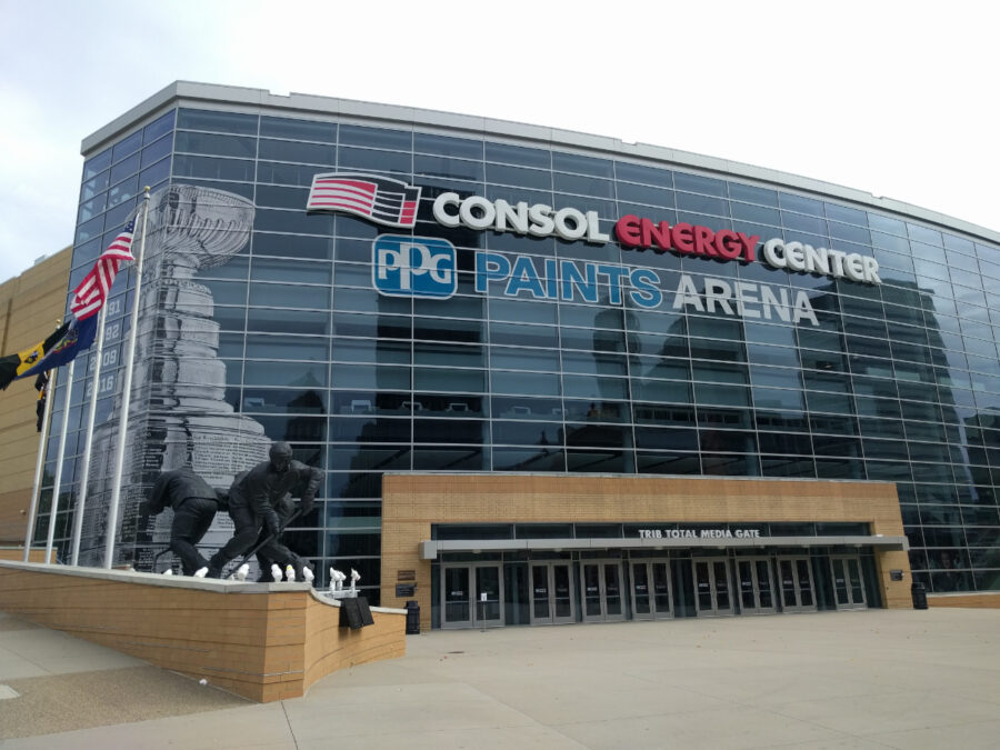 Exterior view of PPG Paints Arena, showcasing its modern architecture and large glass facade against a clear blue sky.
