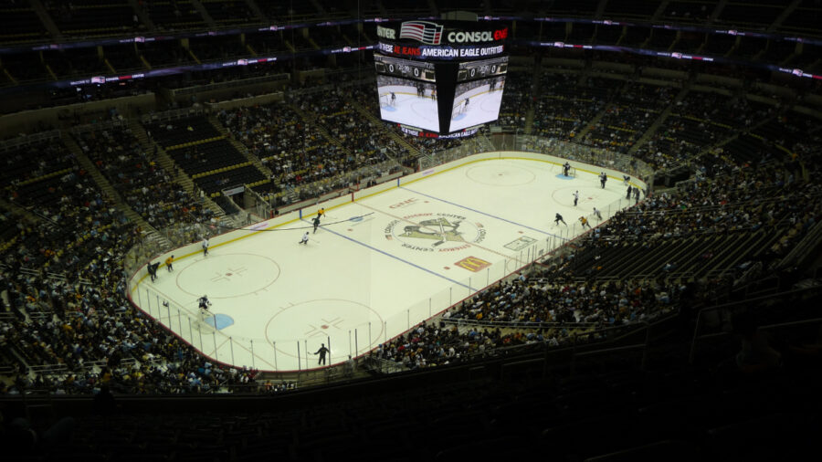 Interior view of PPG Paints Arena during a live game, showcasing fans, players, and vibrant arena lighting.
