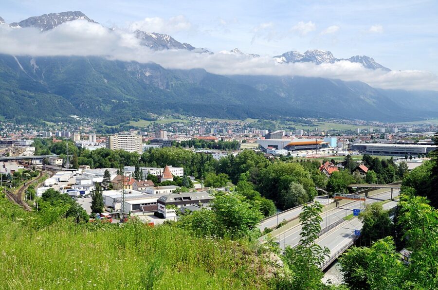 Pradl, Innsbruck, Austria: a train travels through the city with a majestic mountain in the background.