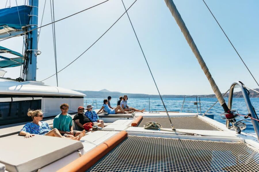 Passengers relax on the deck of a catamaran, enjoying a premium sailing experience in Santorini.