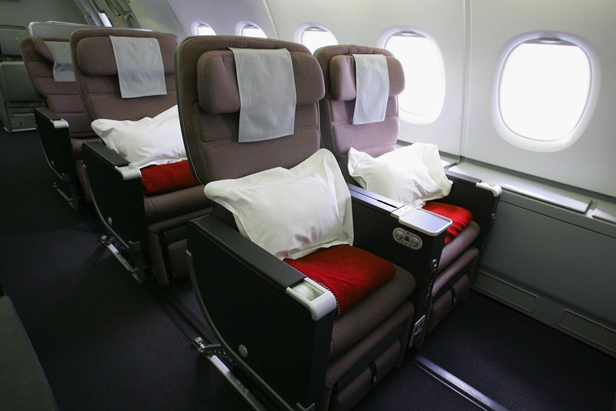 Premium airplane cabin seating with plush seats, pillows, decorative cushions, and natural light.