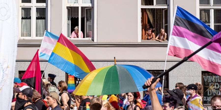 LGBTQ+ Pride parade celebration with diverse crowd, colorful flags, promoting inclusivity and community.