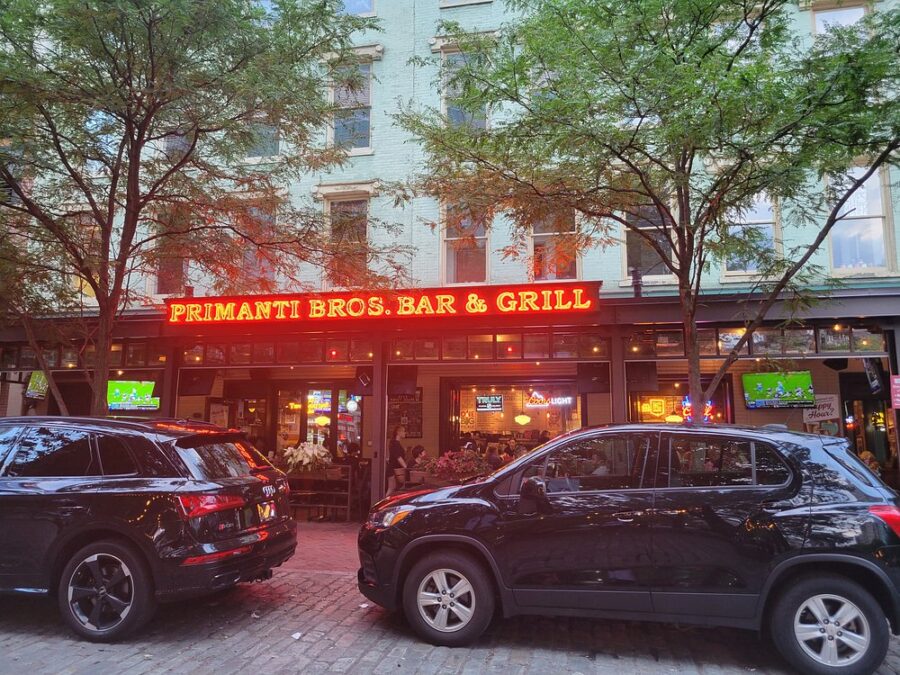 Exterior view of Primanti Brothers in Pittsburgh, featuring a vibrant neon sign illuminating the entrance