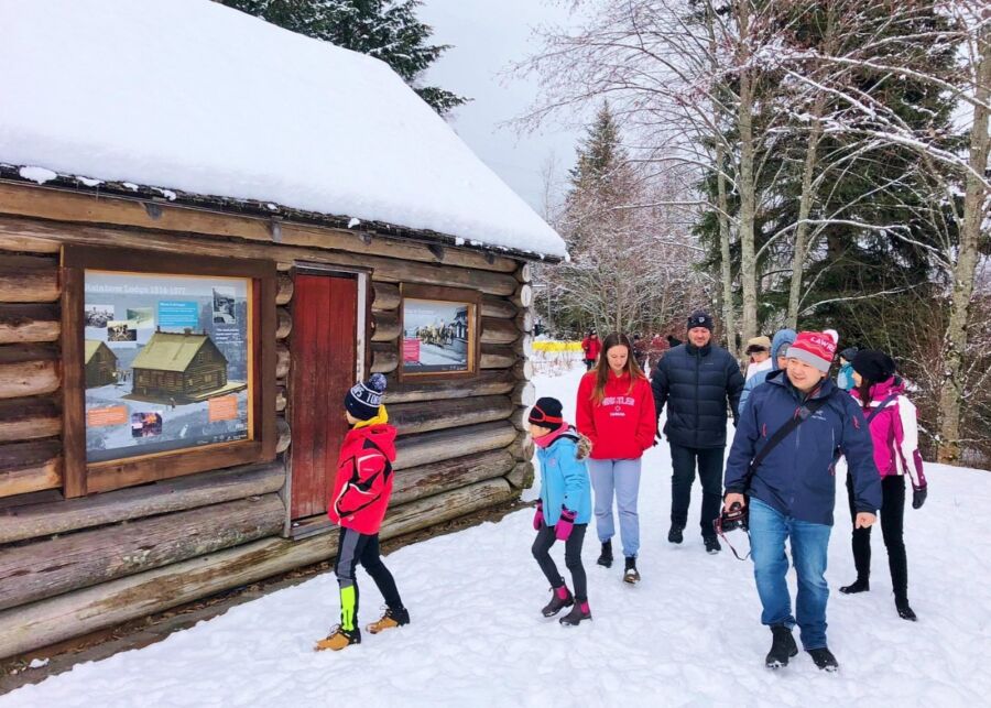 Tour participants stand together in front of a log cabin, enjoying their private sightseeing experience in Whistler