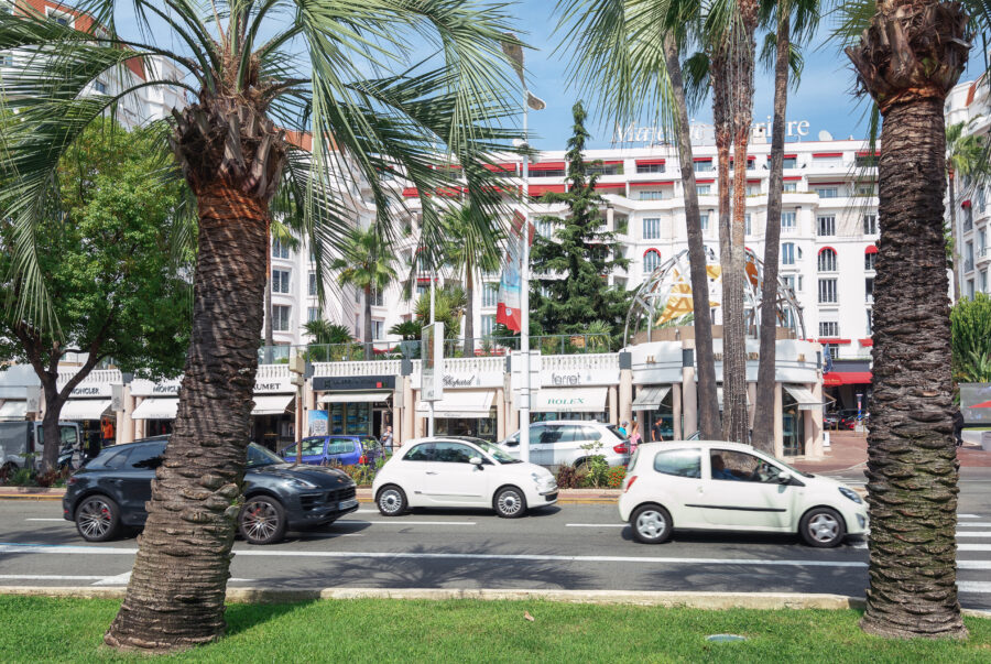 Scenic view of Promenade de la Croisette in Cannes, lined with palm trees, luxury shops, and the Mediterranean Sea
