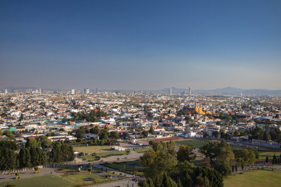 Panoramic view of Cholula, Puebla, highlighting its historic buildings and the backdrop of the Popocatépetl volcano 