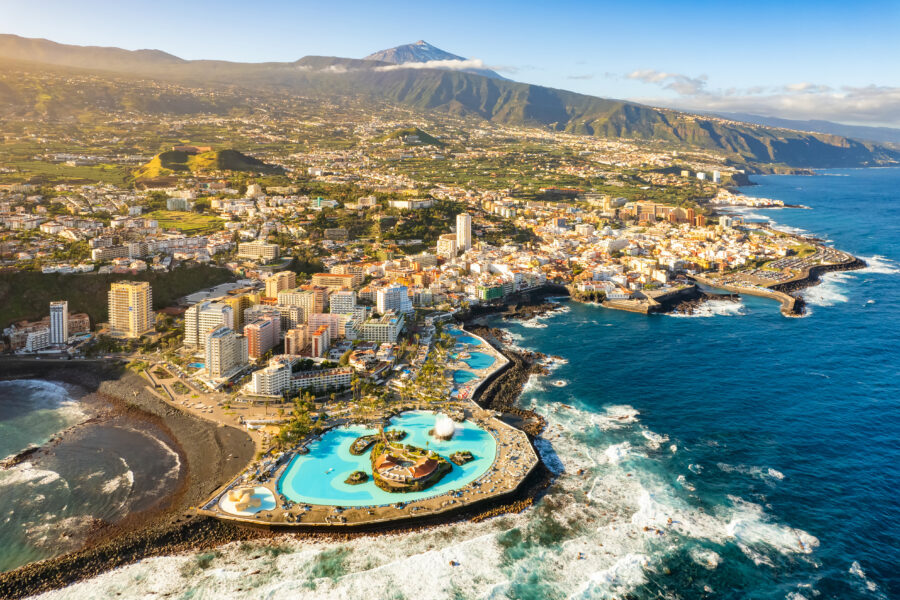 Aerial view of Puerto de la Cruz, showcasing the coastline, city layout, and surrounding mountains in Tenerife, Spain.