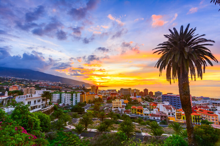 Scenic sunset view over Puerto de la Cruz, Tenerife, showcasing the city and surrounding landscape in warm hues.