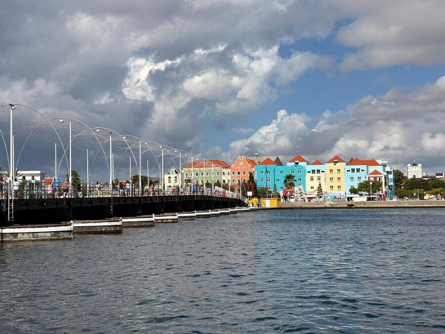 Colorful buildings line a pier in Punda, Curacao, with a bridge in the foreground, showcasing a beautiful Caribbean view.
