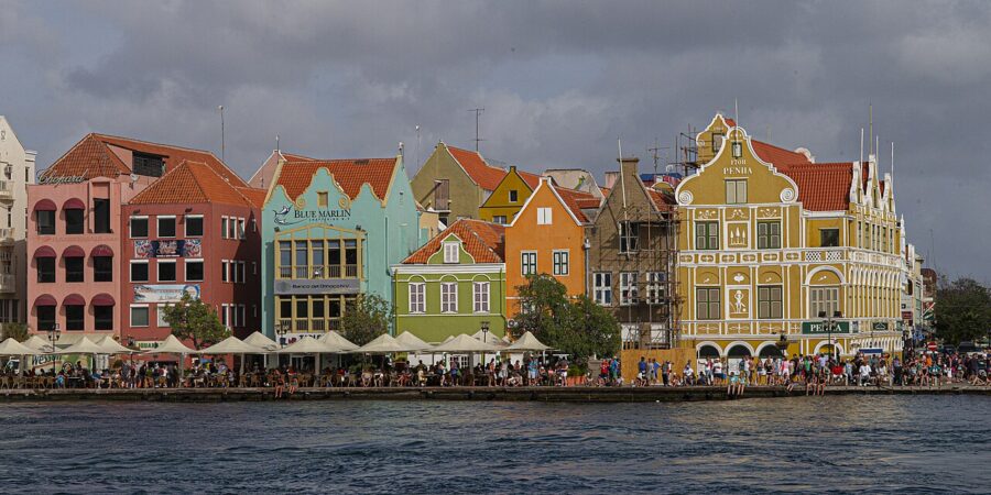 Colorful buildings line the water in Punda, Willemstad, Curacao, creating a picturesque waterfront scene.
