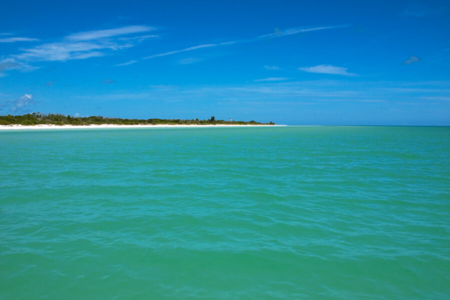 Scenic view of the ocean from a boat near Punta Mosquito, Mexico, showcasing clear blue waters and a sunny sky.