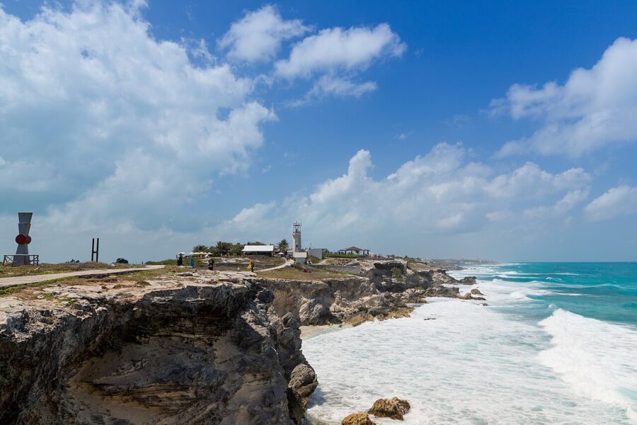Scenic lighthouse on a cliff at Punta Sur, Isla Mujeres, with the vast ocean stretching out in the background.