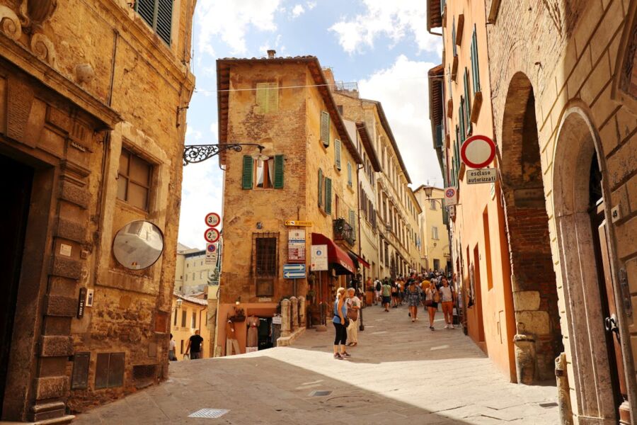 Charming Montepulciano Italian street scene with rustic buildings, pedestrians, shops, cafés, and outdoor dining.