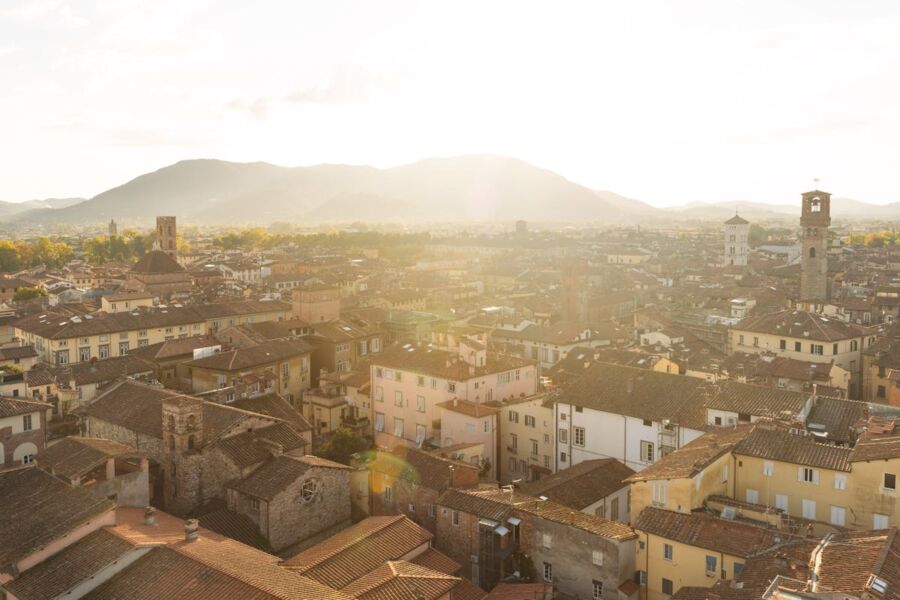 Breathtaking Lucca cityscape with historic architecture, mountains, and golden morning light.