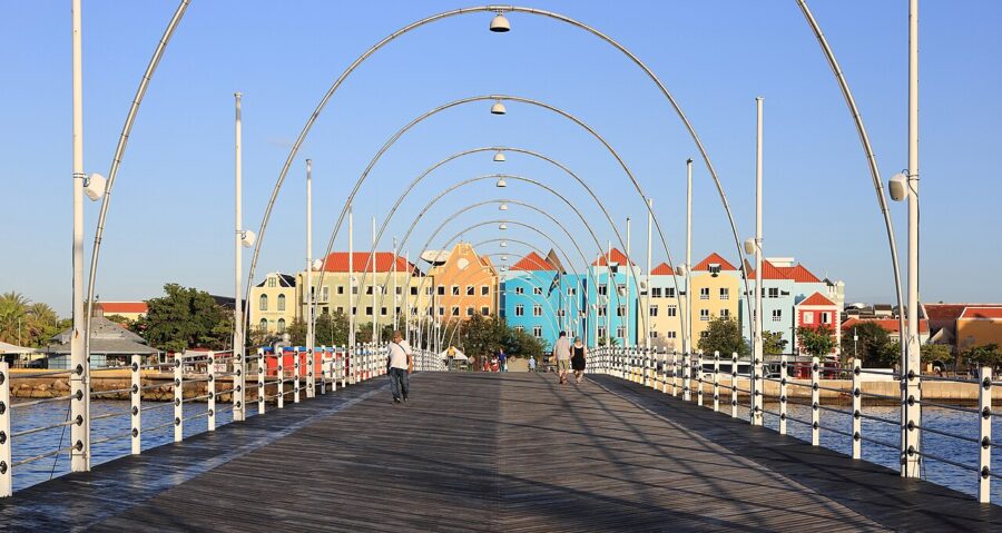 Queen Emma Bridge in Curacao, surrounded by a lively array of colorful buildings in the background.

