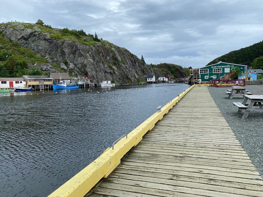 Scenic wooden boardwalk extends to a dock with picnic tables at Quidi Vidi Lake, St. John's, Canada.