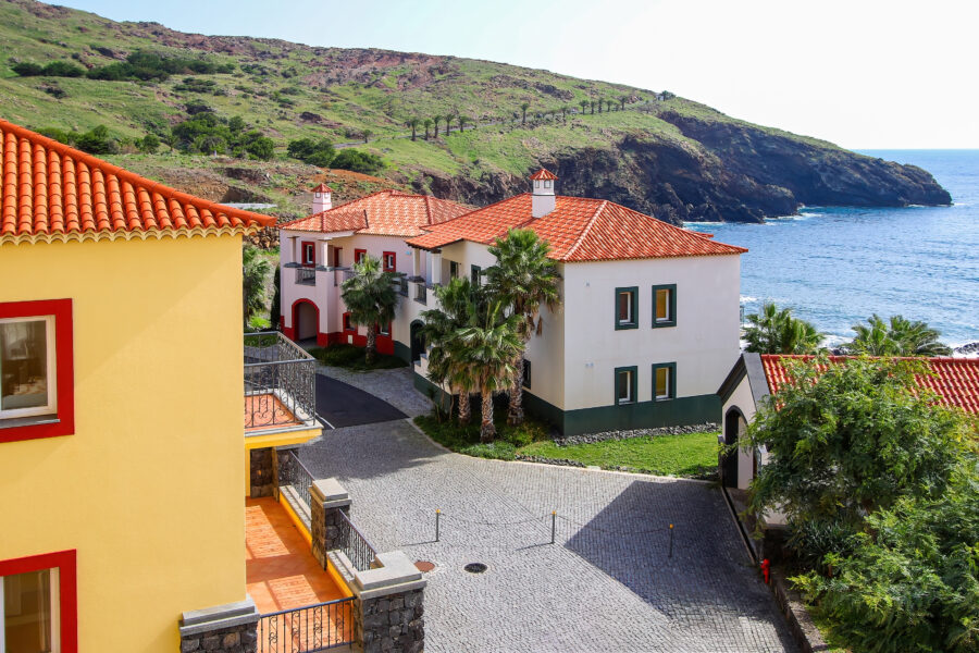 Panoramic view of Funchal, Madeira Island, showcasing vibrant buildings and lush hills against a clear blue sky.
