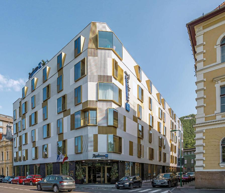 Radisson Blu Aurum Hotel on the corner of a street in Brasov, showcasing its modern architecture and inviting entrance.