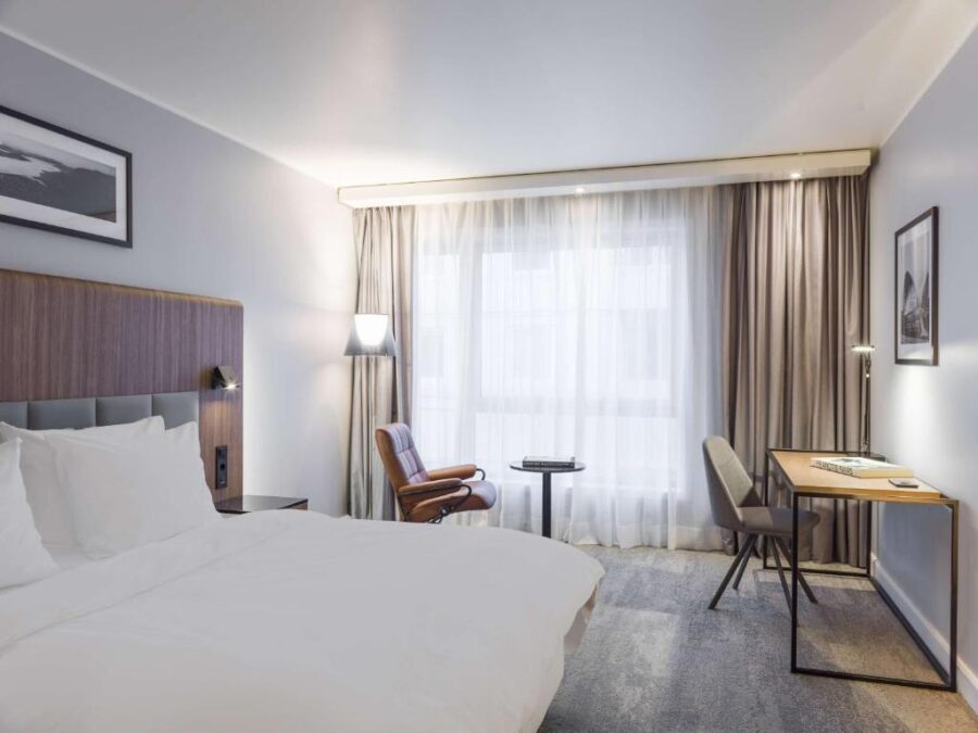 Hotel room at Radisson Blu Tromsø, Norway, featuring a bed, desk, and chair in a modern design.
