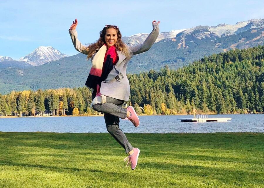 Woman leaps into the air with arms wide open at Rainbow Park, Alta Lake, in Whistler, British Columbia.
