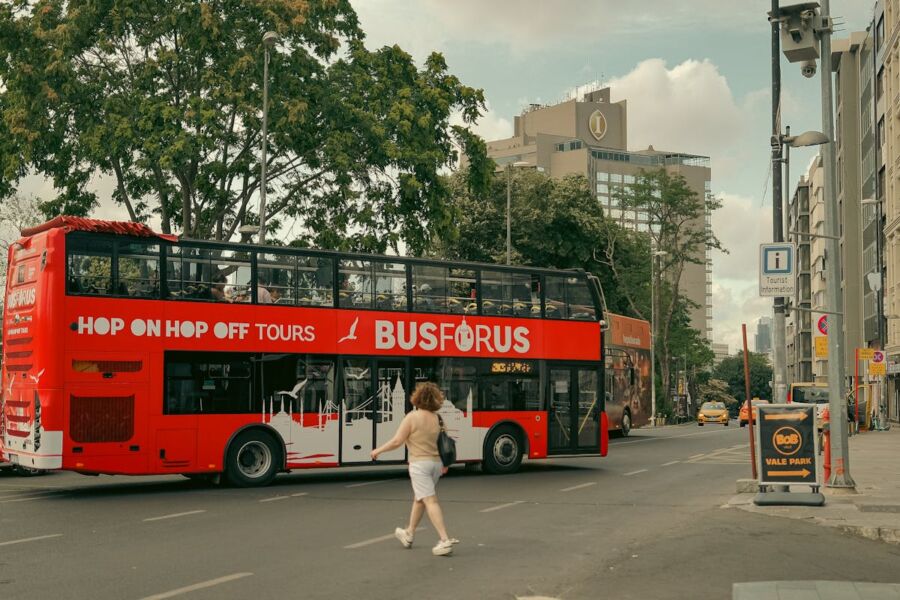 Montreal Red double-decker bus in vibrant city with modern buildings and bustling streets.