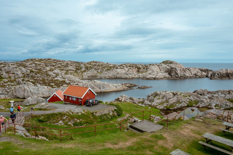 Red coastal cottages on rocky shore overlooking calm bay and granite islands.