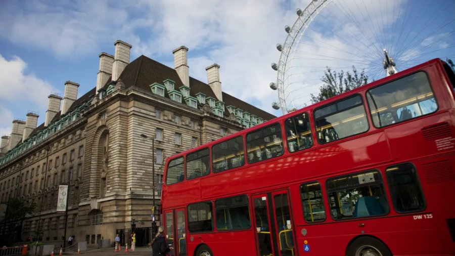 Red double-decker bus on London South Bank with London Eye and historic riverside building.