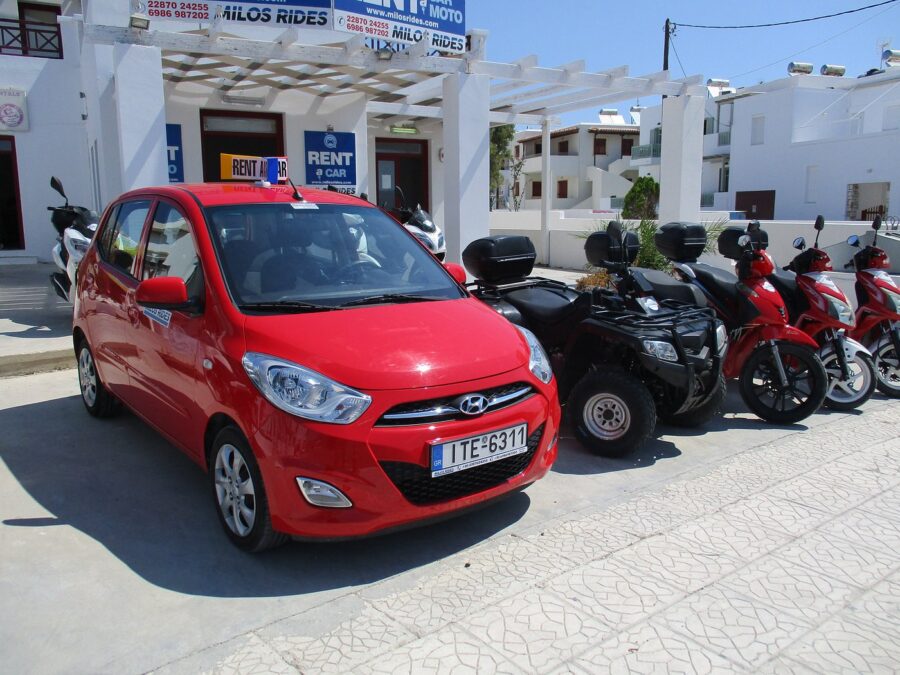 Affordable red hatchback car rental with scooters and ATV in Milos.