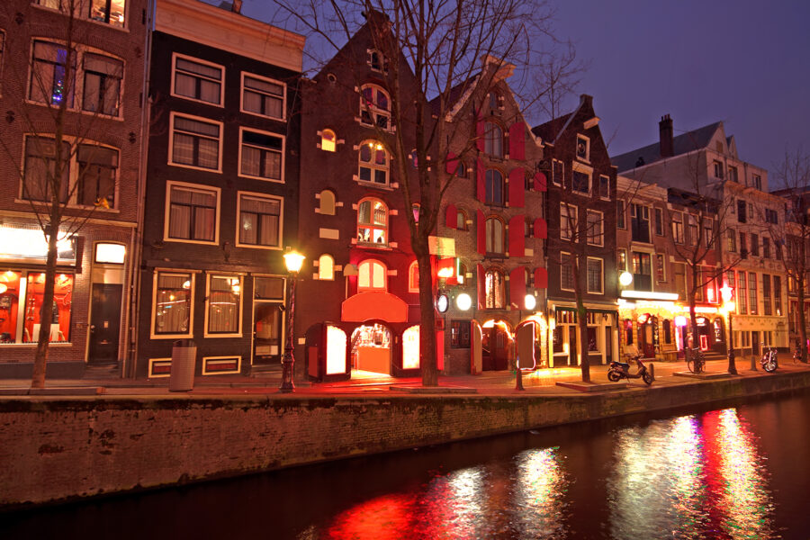 Amsterdam's Red Light District at night, showcasing glowing windows and vibrant streets bustling with activity