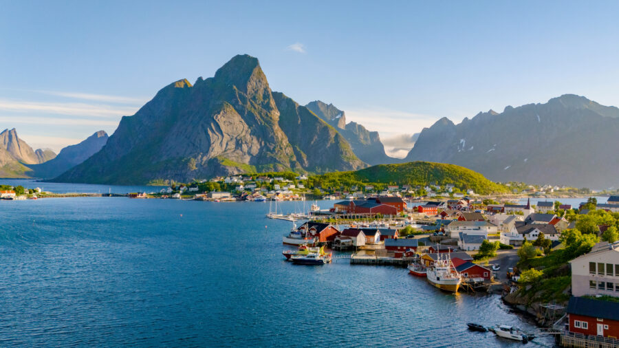 Breathtaking coastal view of Reine, showcasing the dramatic cliffs and serene waters of the Lofoten Islands, Norway.
