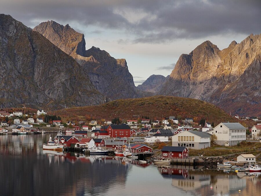 Reine harbor in Norway, showcasing charming houses and majestic mountains rising in the background.