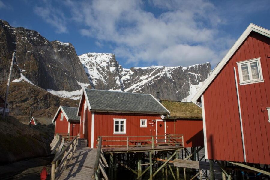 Scenic view of red houses against a mountain in Reine Rorbuer, Norway, highlighting the region's natural beauty.