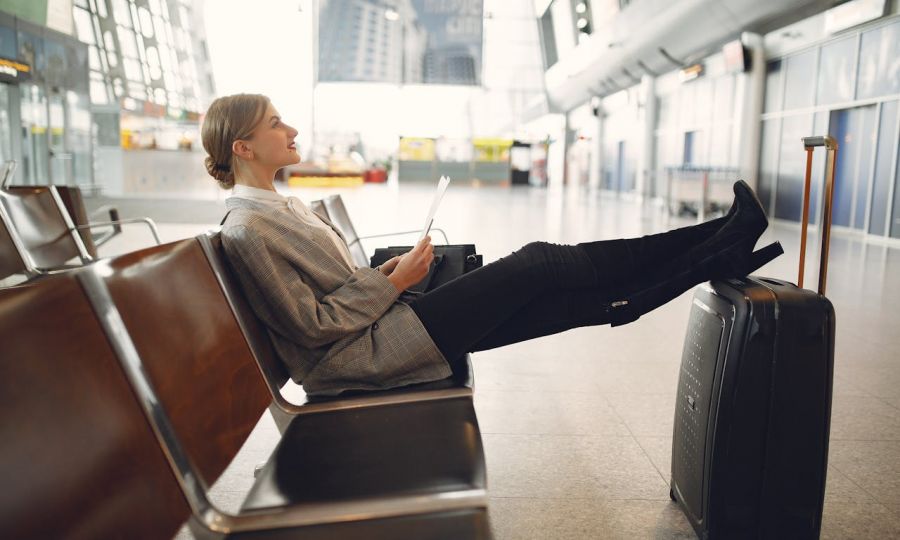 Chic traveler in airport lounge, blending style, relaxation, and travel planning.