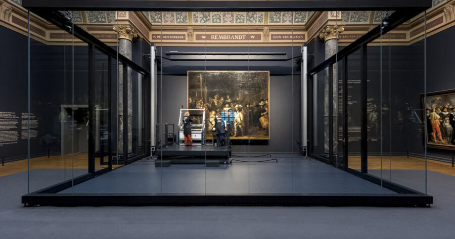 Rembrandts The Night Watch exhibited in a sophisticated art gallery with modern technology integration.