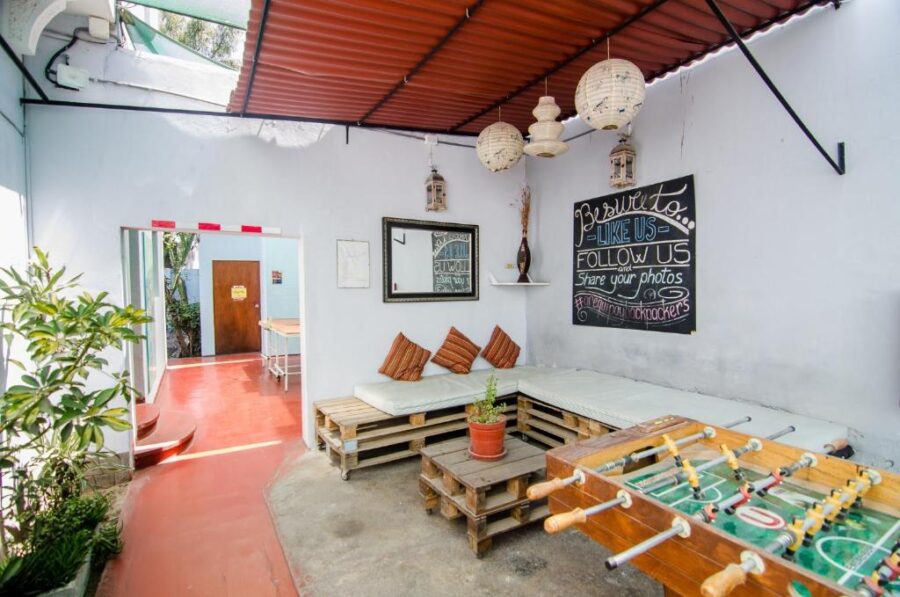Cozy Arequipay Hostel lounge with pallet sofa, plants, foosball table, and rustic semi-outdoor decor.