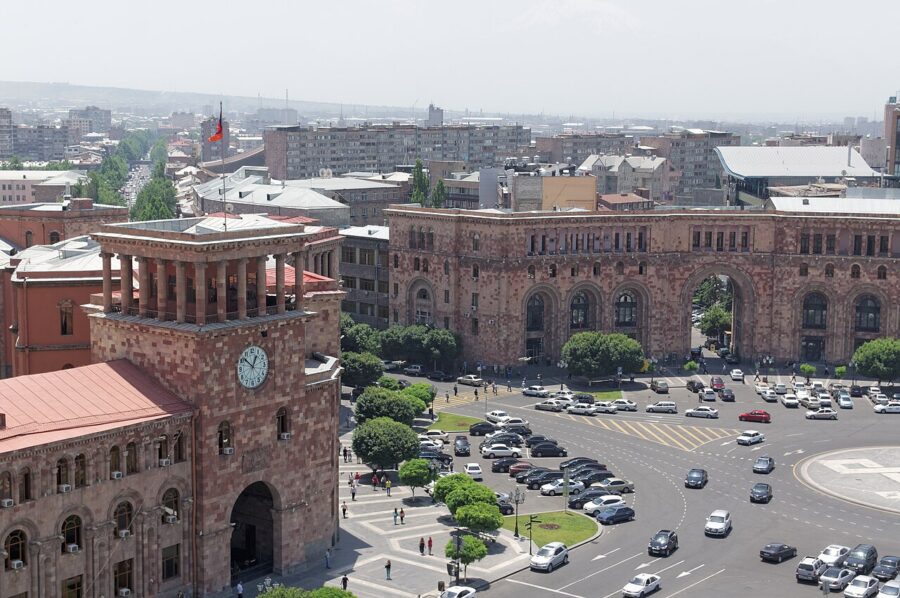 Panoramic scene of Republic Square in Yerevan, Armenia, featuring heavy traffic and a skyline of modern buildings.