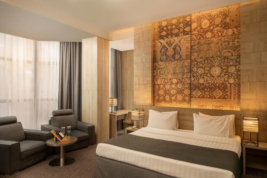 Hotel room at Republica Hotel Yerevan featuring a large bed and an impressive wall painting.
