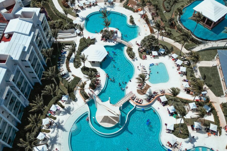 Aerial view of luxurious resort pools, palm trees, lounges, and modern architecture.