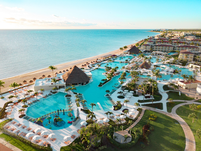 Aerial view of luxury beachfront resort with pools, cabanas, and tropical scenery.