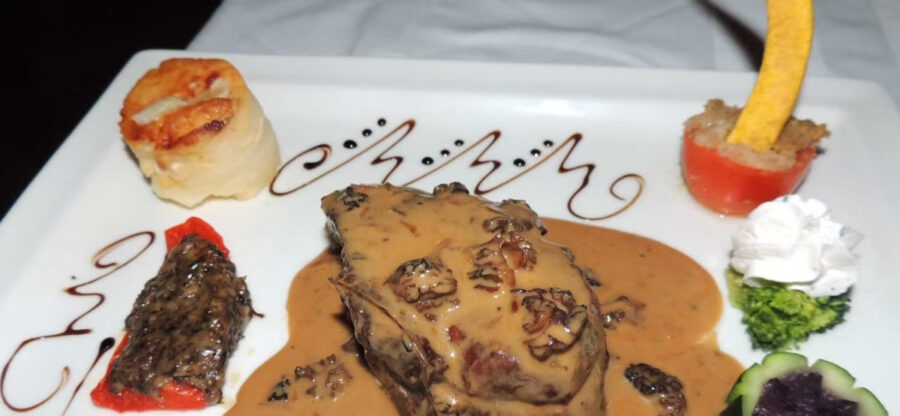 Plate featuring meat, colorful vegetables, and sauce, served at Restaurant L'Auberge Gourmande in St. Martin.
