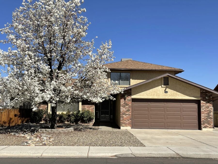 Lovely home with a large tree out front, surrounded by the beauty of Lake Powell and Antelope Canyon.