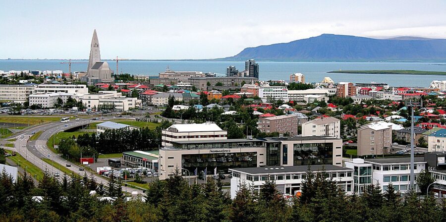 Reykjavík cityscape featuring numerous buildings with a mountain backdrop under a clear blue sky.