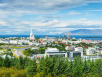 Panoramic view of Reykjavik, Iceland, showcasing colorful buildings and the surrounding mountains under a clear blue sky.