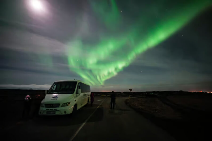 Reykjavík minibus parked under stunning aurora lights, highlighting the magical Northern Lights display.
