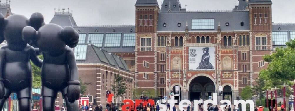 Amsterdams Rijksmuseum scene: Gothic architecture, I amsterdam sign, sculptures, visitors.