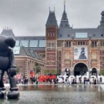 Amsterdams Rijksmuseum scene: Gothic architecture, I amsterdam sign, sculptures, visitors.