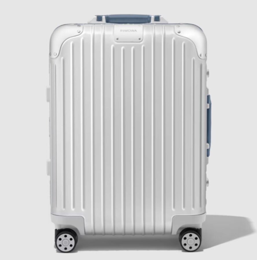 Rimowa Cabin Twist, a white wheeled suitcase, contrasts sharply with a black background.
