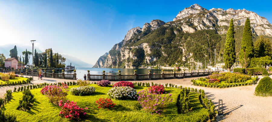 Lush garden landscape at Riva del Garda, showcasing vibrant flowers and greenery with Lake Garda in the background